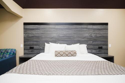 a bedroom with a white bed with a wooden headboard at Sapphire Inn & Suites in Channelview