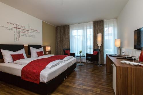 ein Hotelzimmer mit einem großen Bett und einem Schreibtisch in der Unterkunft Weingut Schreieck VINOTEL & GUTSHAUS in Sankt Martin