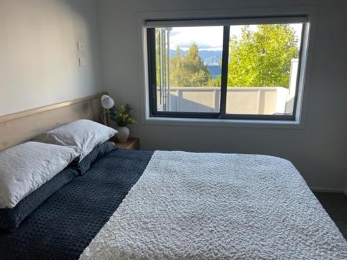 a bedroom with a bed and a large window at Lakeview in Lake Hawea