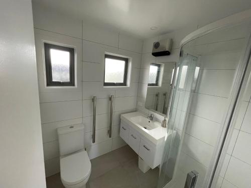 a white bathroom with a toilet and a sink at Lakeview in Lake Hawea