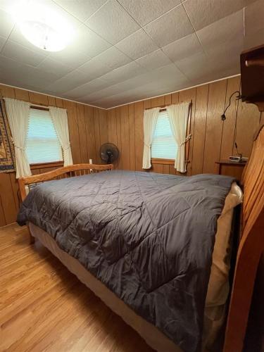 a bedroom with a bed and two windows at MOOSEY ON INN LIMIT 8 cottage in Hillside