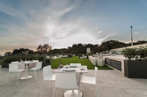 a patio with white tables and chairs on a roof at Hotel Sorli Emocions in Vilassar de Dalt