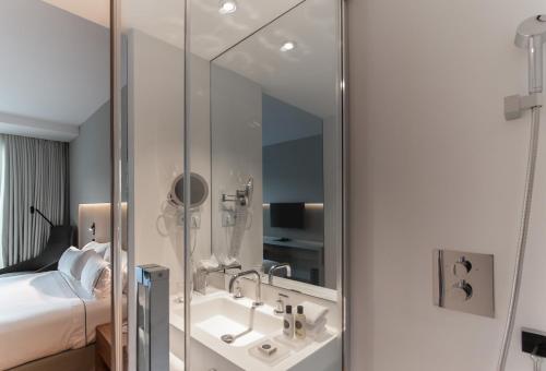a bathroom with a sink and a bed and a mirror at Hotel Sorli Emocions in Vilassar de Dalt