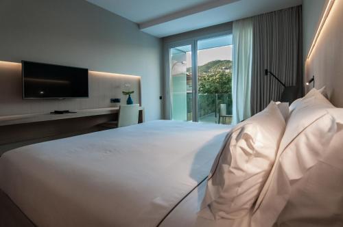 a bedroom with a large white bed with a large window at Hotel Sorli Emocions in Vilassar de Dalt