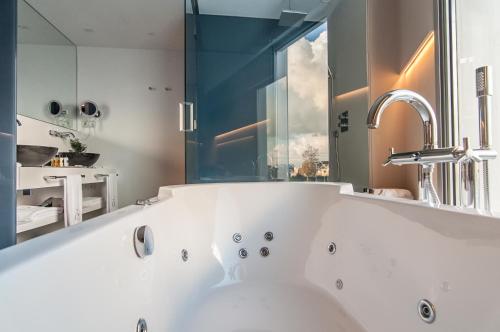 a white bath tub in a bathroom with a mirror at Hotel Sorli Emocions in Vilassar de Dalt