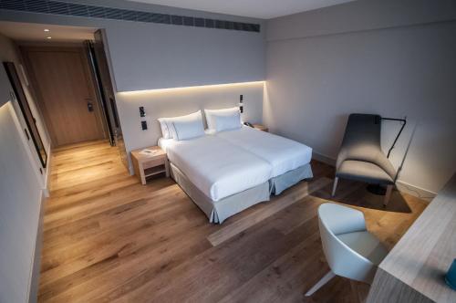a hotel room with a white bed and a chair at Hotel Sorli Emocions in Vilassar de Dalt
