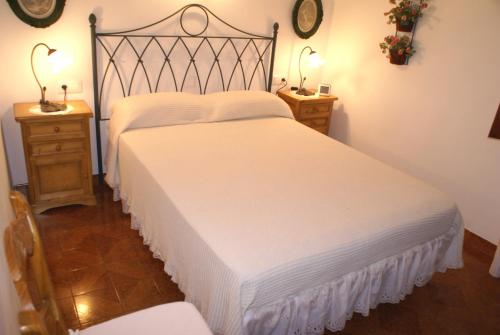 カラ・ブランカにあるVilla Ponderosaのベッドルーム1室(白い大型ベッド1台、ナイトスタンド2台付)