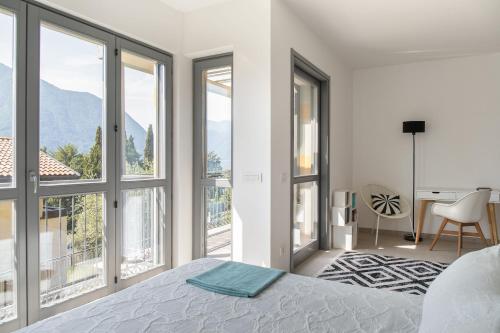 a bedroom with white walls and windows and a bed at Casa degli Ulivi - Ossuccio - Tremezzina in Isola Comacina