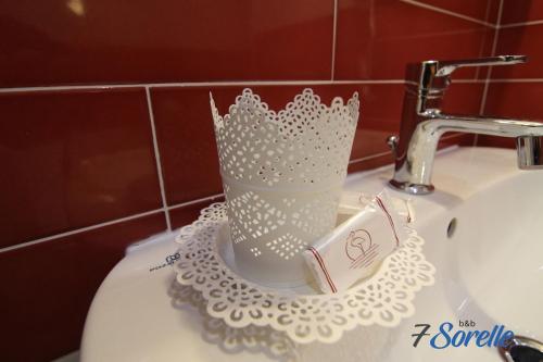 a white toothbrush holder sitting on top of a sink at "7 SORELLE B&B" camere in pieno centro città con bagno privato, FREE HIGH SPEED WI-FI, NETFLIX in Cosenza