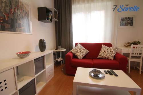 a living room with a red couch and a table at "7 SORELLE B&B" camere in pieno centro città con bagno privato, FREE HIGH SPEED WI-FI, NETFLIX in Cosenza