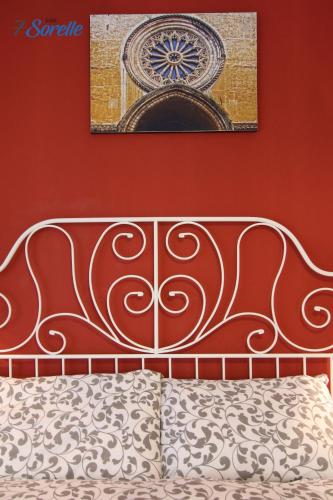 a bed with a metal headboard and a painting above it at "7 SORELLE B&B" camere in pieno centro città con bagno privato, FREE HIGH SPEED WI-FI, NETFLIX in Cosenza
