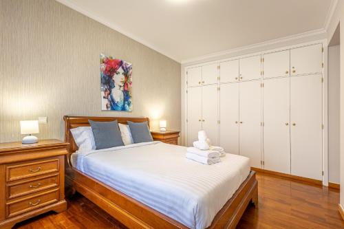 een slaapkamer met een groot bed en witte kasten bij Machico City Apt in Machico