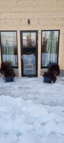 two chairs sitting in the snow in front of a building at Fjällstugan in Sälen