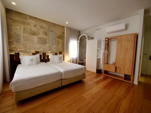 1 dormitorio con 1 cama grande y pared de piedra en Porta Nobre - Exclusive Living Hotel, en Oporto