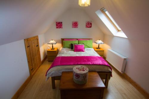 a bedroom with a bed with pink sheets and green pillows at The Thatched Cottage B&B in Claregalway