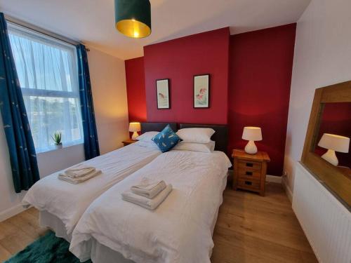 um quarto com uma grande cama branca com paredes vermelhas em Cheerful 3 bedroom home with garden! em Torquay