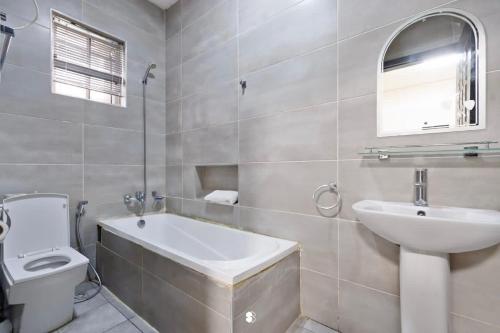 bagno con lavandino, vasca e servizi igienici di Sophisticated 4-Bedroom Condo in VI a Igboshere