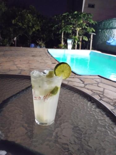a drink with a lime on a table next to a pool at Pousada Avenida in Tibagi