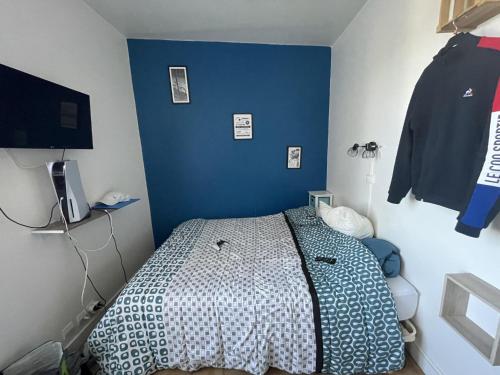 1 dormitorio con 1 cama con pared azul en Meublé de Tourisme dans parc arboré 1000m2 - Sejour-la-Roche Eperon, en La Roche-Posay
