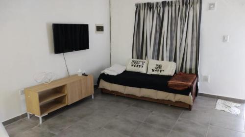 Dormitorio pequeño con cama y TV en Depto. Playa Unión en Playa Unión