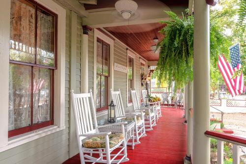 um alpendre com cadeiras de balanço brancas numa casa em Cedar House Inn em Saint Augustine