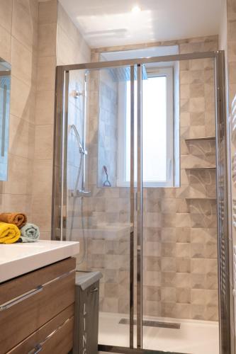 une salle de bain avec une douche avec une porte vitrée dans l'établissement Le 11 à 5 min de l'hypercentre d'Epernay 6 personnes, à Épernay