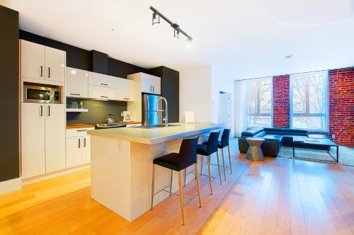 a kitchen with white cabinets and a bar with stools at Les Lofts St-Joseph - Par Les Lofts Vieux-Québec in Quebec City