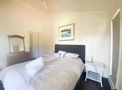 a bedroom with a large white bed and a mirror at Coconuts - 3 bedroom 3 bathroom townhouse with tennis court in Nelson Bay