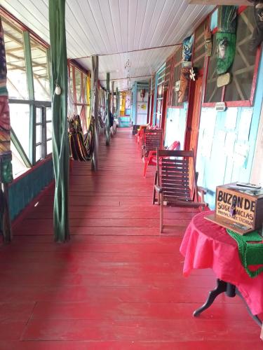 un vagone ferroviario con pavimenti e sedie rossi e un tavolo di Hostal tachiwa a Puerto Nariño