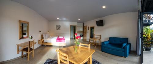 ein Schlafzimmer mit einem Bett, einem blauen Sofa und einem Tisch in der Unterkunft Las Terrazas de Dana Boutique Lodge & Spa in Mindo