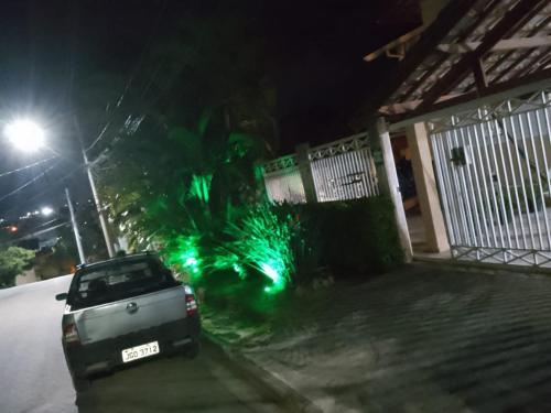 une voiture garée devant une maison avec des feux verts dans l'établissement Hospedagem Maria Joana, à Atibaia