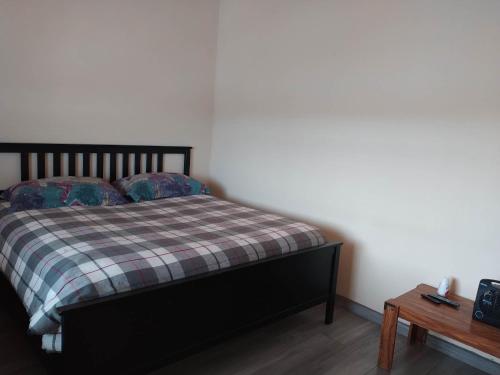 Un dormitorio con una cama con una manta a cuadros y una mesa en ENSVACATION, en Ensenada
