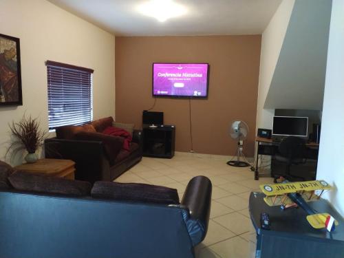 sala de estar con sofá y TV de pantalla plana en ENSVACATION, en Ensenada