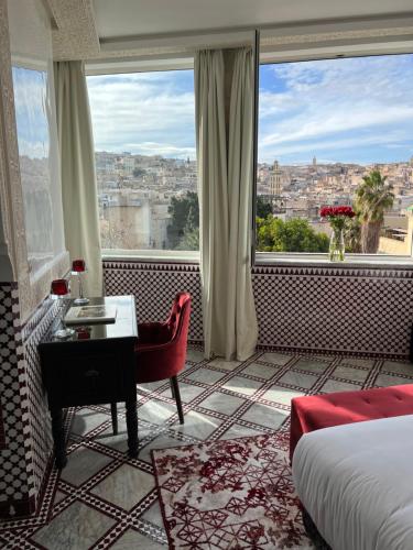 a hotel room with a bed and a desk and a window at Palais De Fès Suites & Spa in Fès