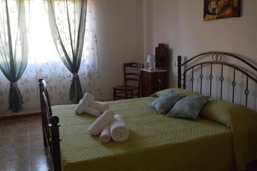 a bedroom with a green bed with towels on it at Su Fassoi Cabras in Càbras