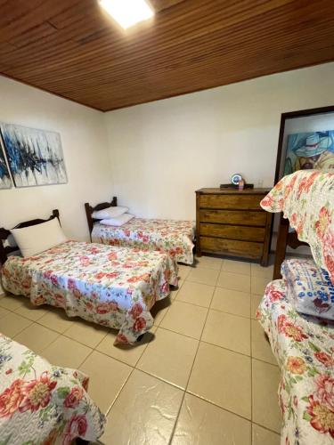 um quarto com três camas e uma cómoda em Casa à beira do lago em Divinópolis