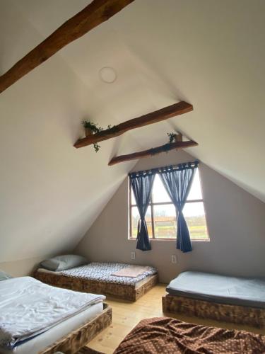 a attic room with two beds and two windows at Kuća za odmor/Party kuća in Lukinić Senovec