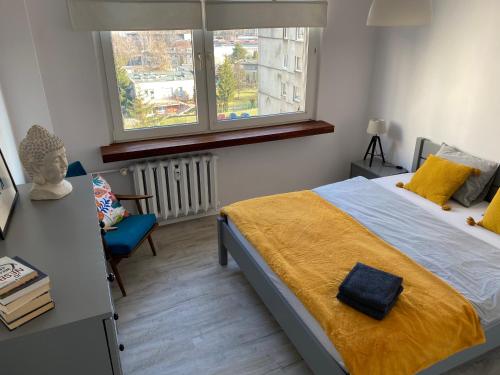 um quarto com uma cama, uma cadeira e uma janela em Słoneczny apartament em Katowice