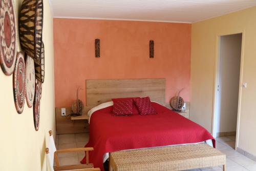 a bedroom with a red bed with red pillows at Oltarcie - Maison d'hôte avec piscine in Espagnac-Sainte-Eulalie