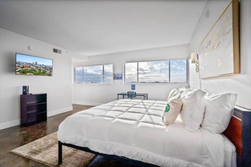 a white bedroom with a large white bed and windows at Heart of Mobile in Mobile