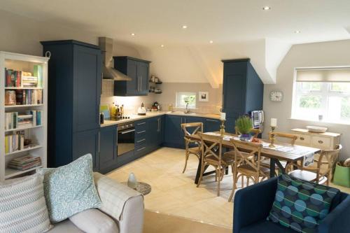 uma cozinha com armários azuis e uma mesa com cadeiras em The Folly Bushmills em Bushmills