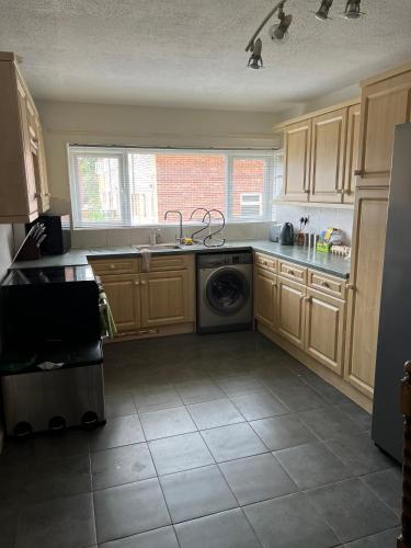 cocina con armarios de madera y lavadora en Fellowes View, en Peterborough