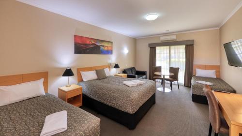 a hotel room with two beds and a desk at Top of the Town Motel & Apartments in Benalla