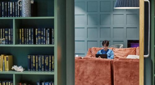 a man sitting on a couch using a laptop at ARK Canary Wharf in London