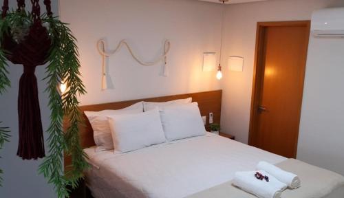 a bedroom with a bed with white pillows and a plant at Lindo Ap Studio em Bananeiras in Bananeiras