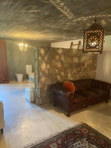 sala de estar con sofá de cuero y pared de piedra en Loft Boutique Chacras de Coria en Luján de Cuyo