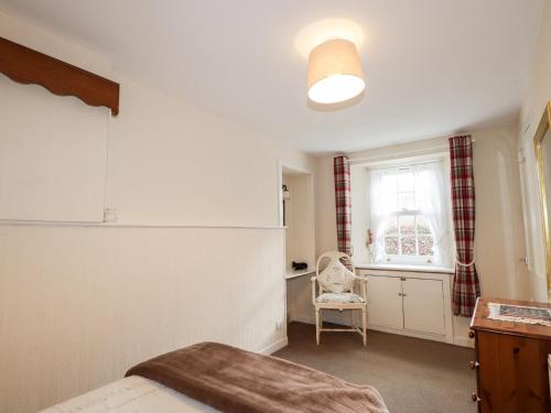 a bedroom with a bed and a window and a chair at Rose Cottage in Strathpeffer