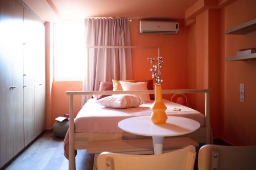 sypialnia z pomarańczowymi ścianami i łóżkiem ze stołem w obiekcie RYB Colour Apartment w mieście Patras