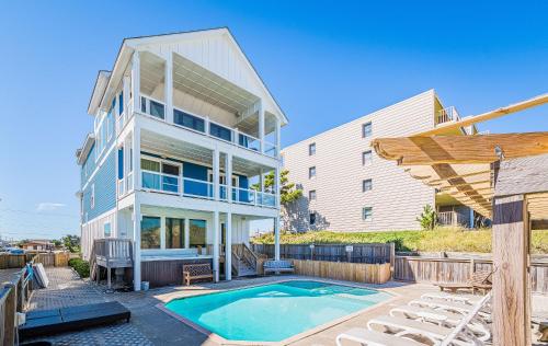 a house with a swimming pool next to a building at Good Karma Retreat - Nags Head MP 15.5, Oceanfront, Elevator, Pool, Hot Tub, Pets OK, Flex Stays in Nags Head