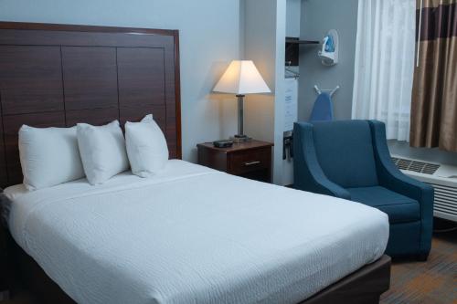 ein Hotelzimmer mit einem Bett und einem blauen Stuhl in der Unterkunft AmericInn by Wyndham Madison WI in Madison